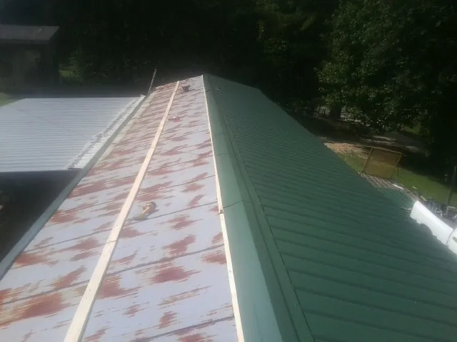 Old rusted panels beside newly installed green metal roofing — Wind Damage Roof Repair by Roofing Brothers in Woodcliff Lake