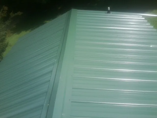 New green metal panels meeting at the ridge of a roof — Flat Roof Repair work by our crew in Woodcliff Lake
