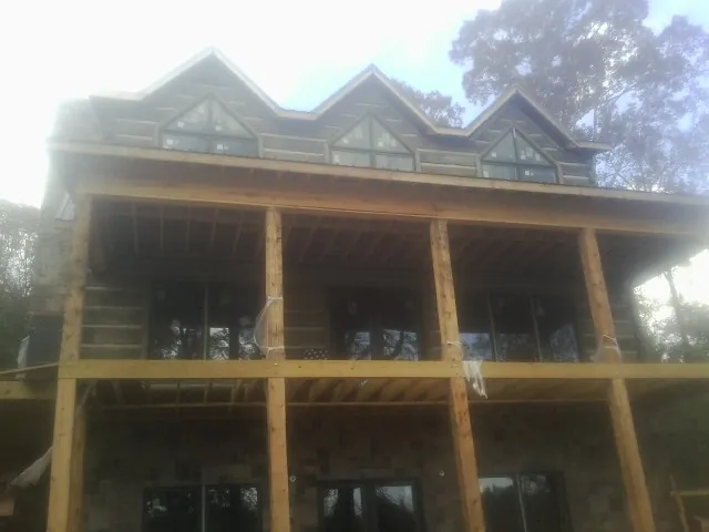 Dormers and porch framing on a large log home under construction — Roof Coating work by our crew in Woodcliff Lake