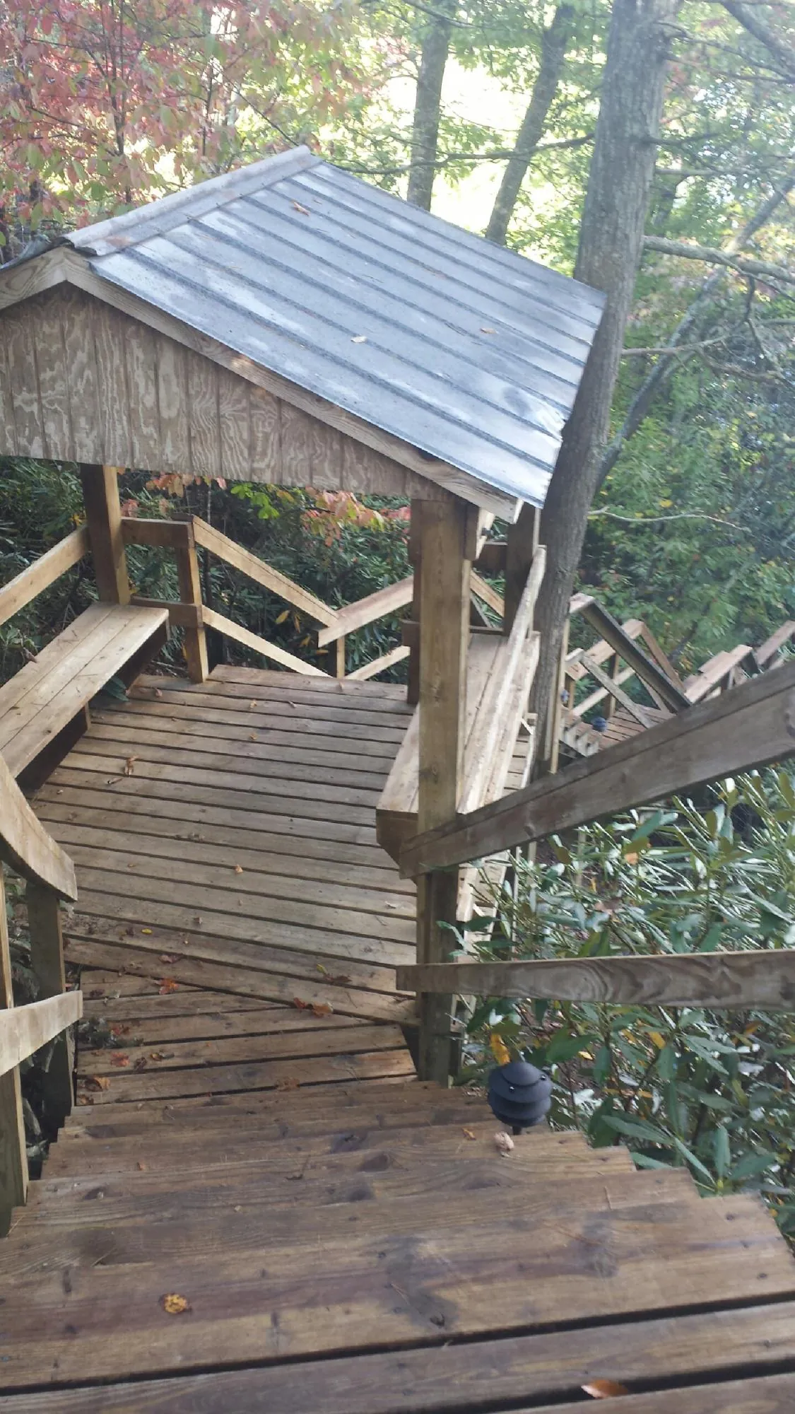 Metal roofed shelter over wooden steps on a wooded walkway — Skylight Repair & Installation work by our crew in Woodcliff Lake