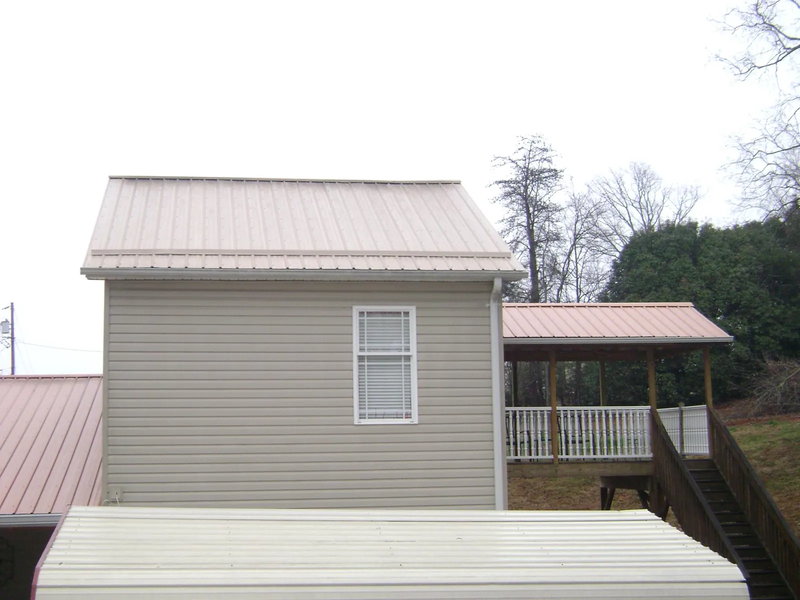 Tan metal roofs on a two story addition and attached porch, from a Roof Replacement job in Woodcliff Lake