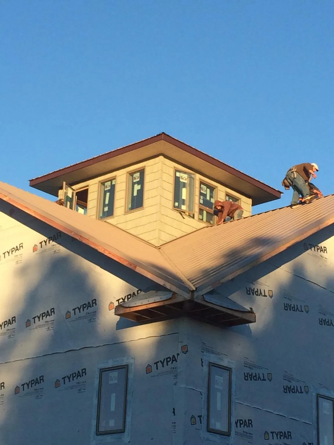 Roofers working around a rooftop cupola on a new metal roof at sunset — Roof Waterproofing in Woodcliff Lake by Roofing Brothers